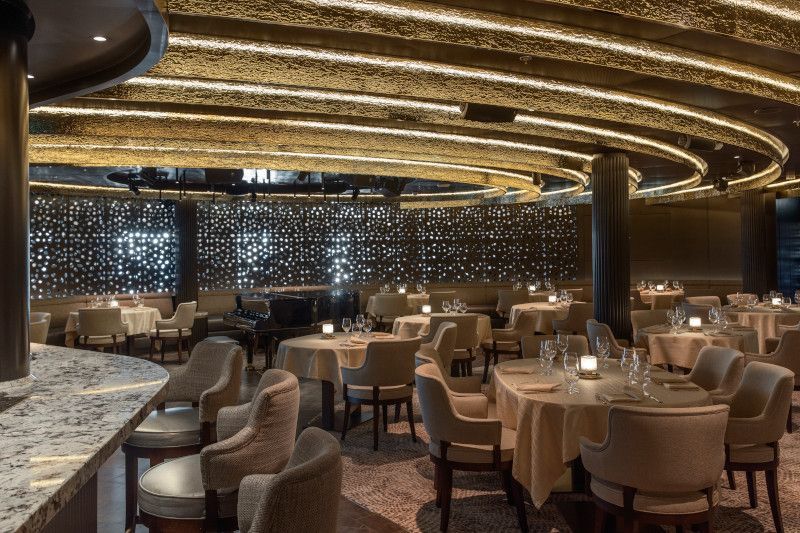 A large dining room with tables and chairs and a bar.