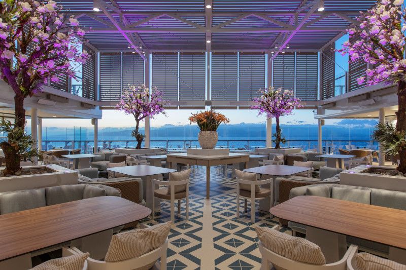 A large room with tables and chairs and a view of the ocean.