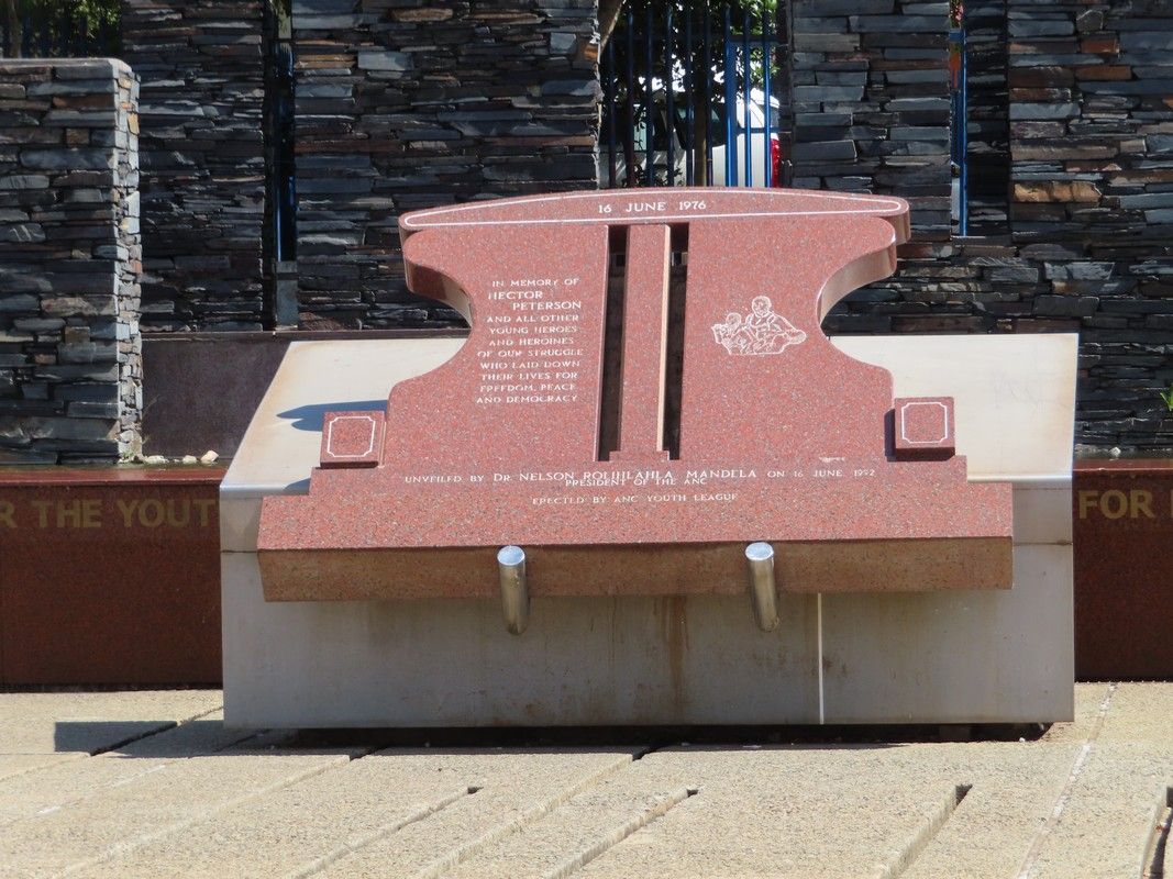 A statue of an anvil is sitting in front of a stone wall