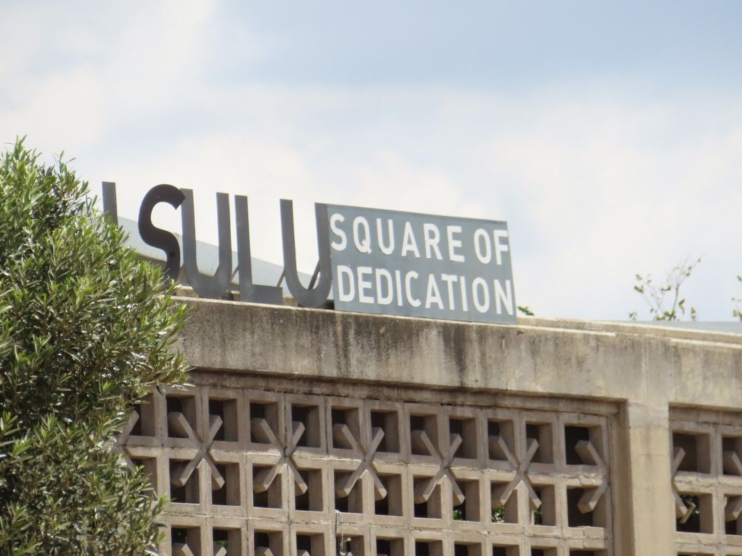 A sign on a building that says square of dedication