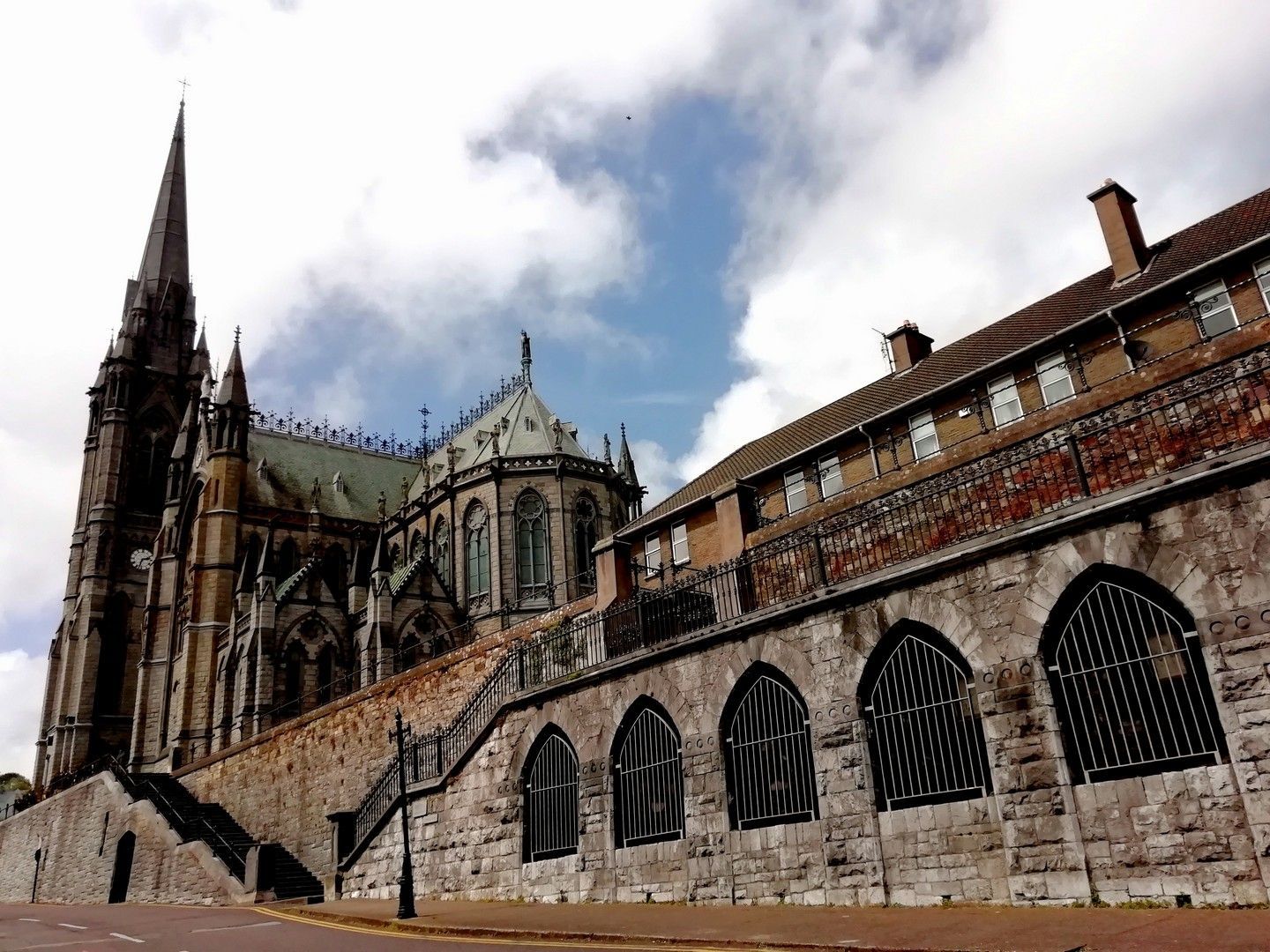 A large building with a steeple is behind a stone wall