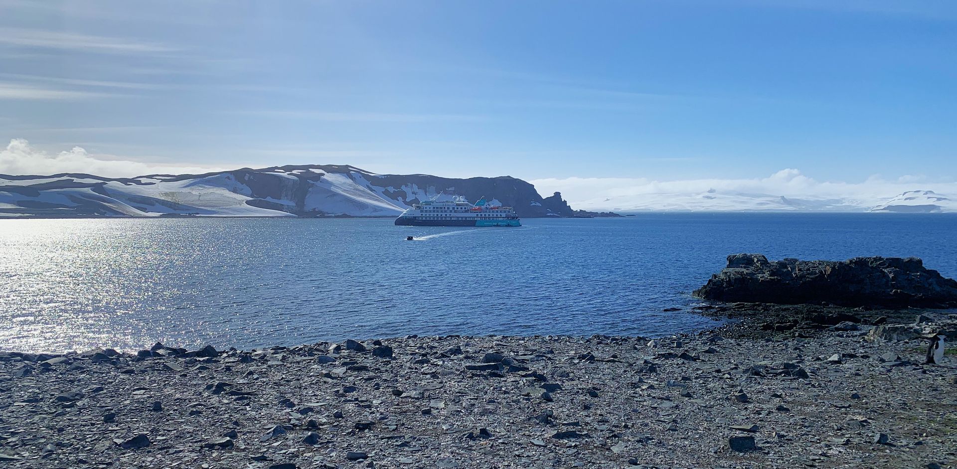 A large body of water with a boat in the distance and a rocky shoreline in the foreground.