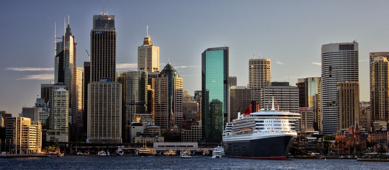A cruise ship is docked in front of a city skyline