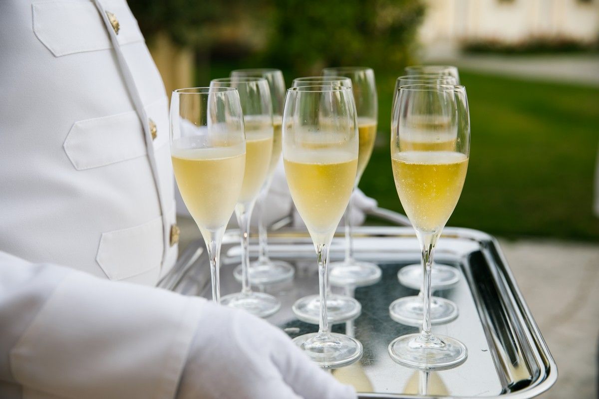 A waiter is holding a tray of champagne glasses.