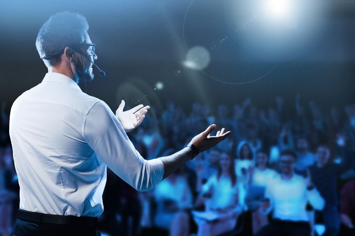 A man is giving a speech in front of a crowd of passengers on a world cruise