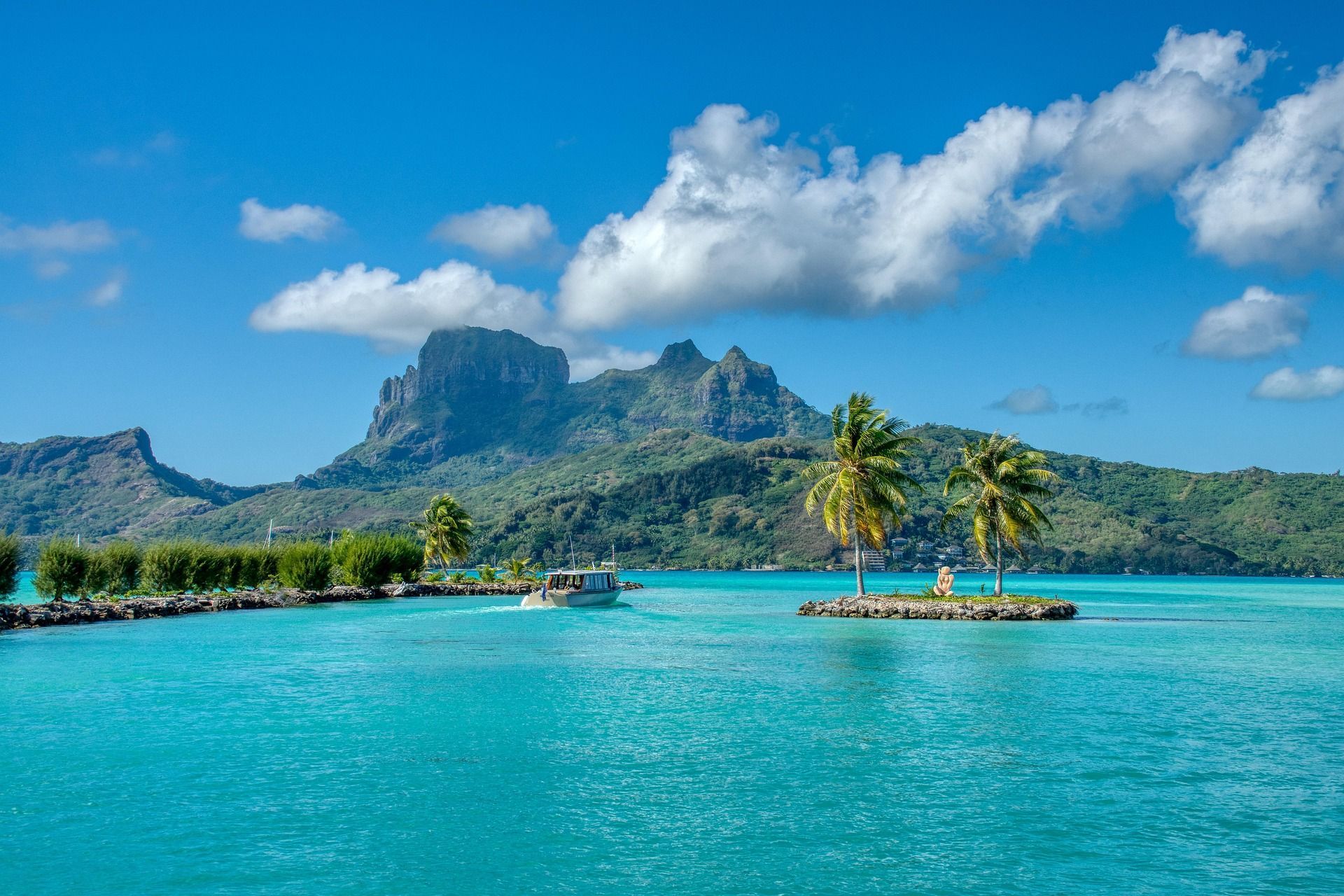 A boat is floating on top of a small island in the middle of the ocean on a world cruise