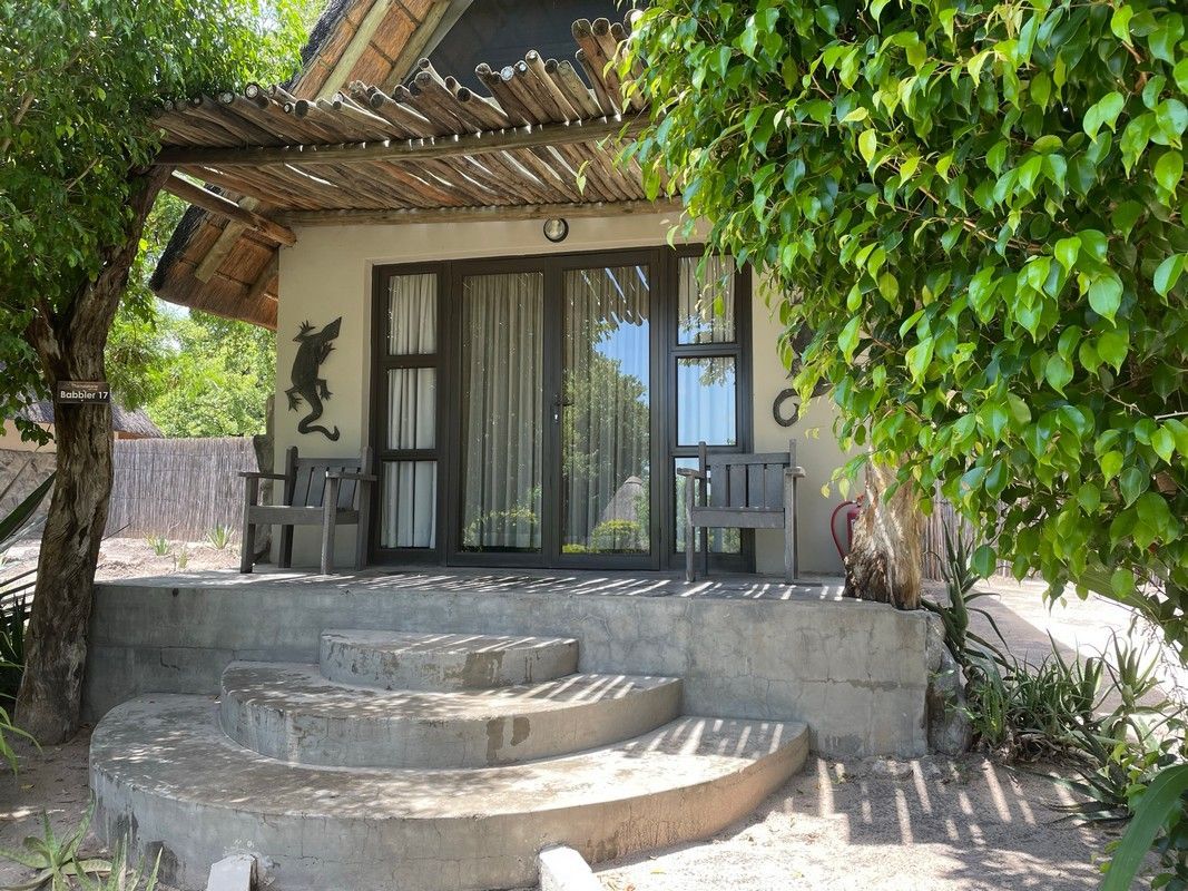 A small house with stairs leading up to it is surrounded by trees.