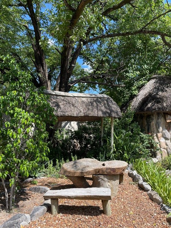 There is a thatched hut in the background and a picnic table in the foreground.