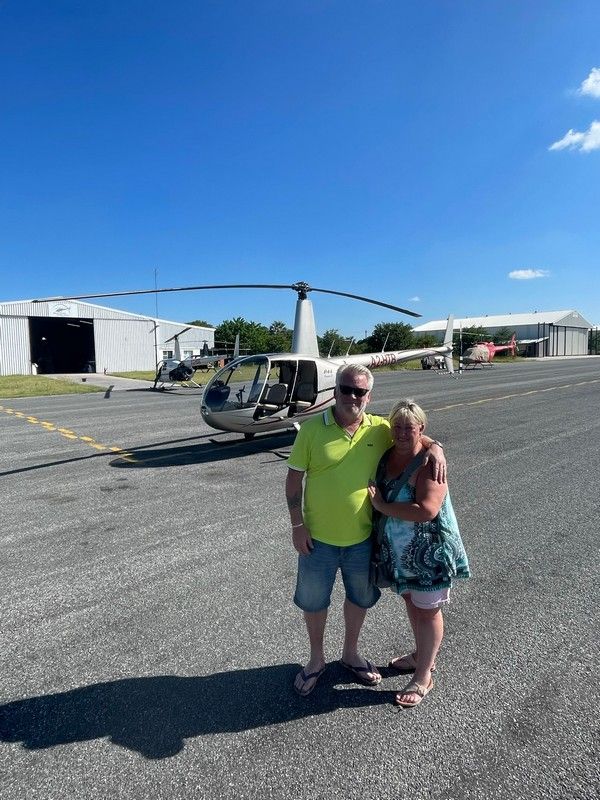 A man and a woman are standing in front of a helicopter.