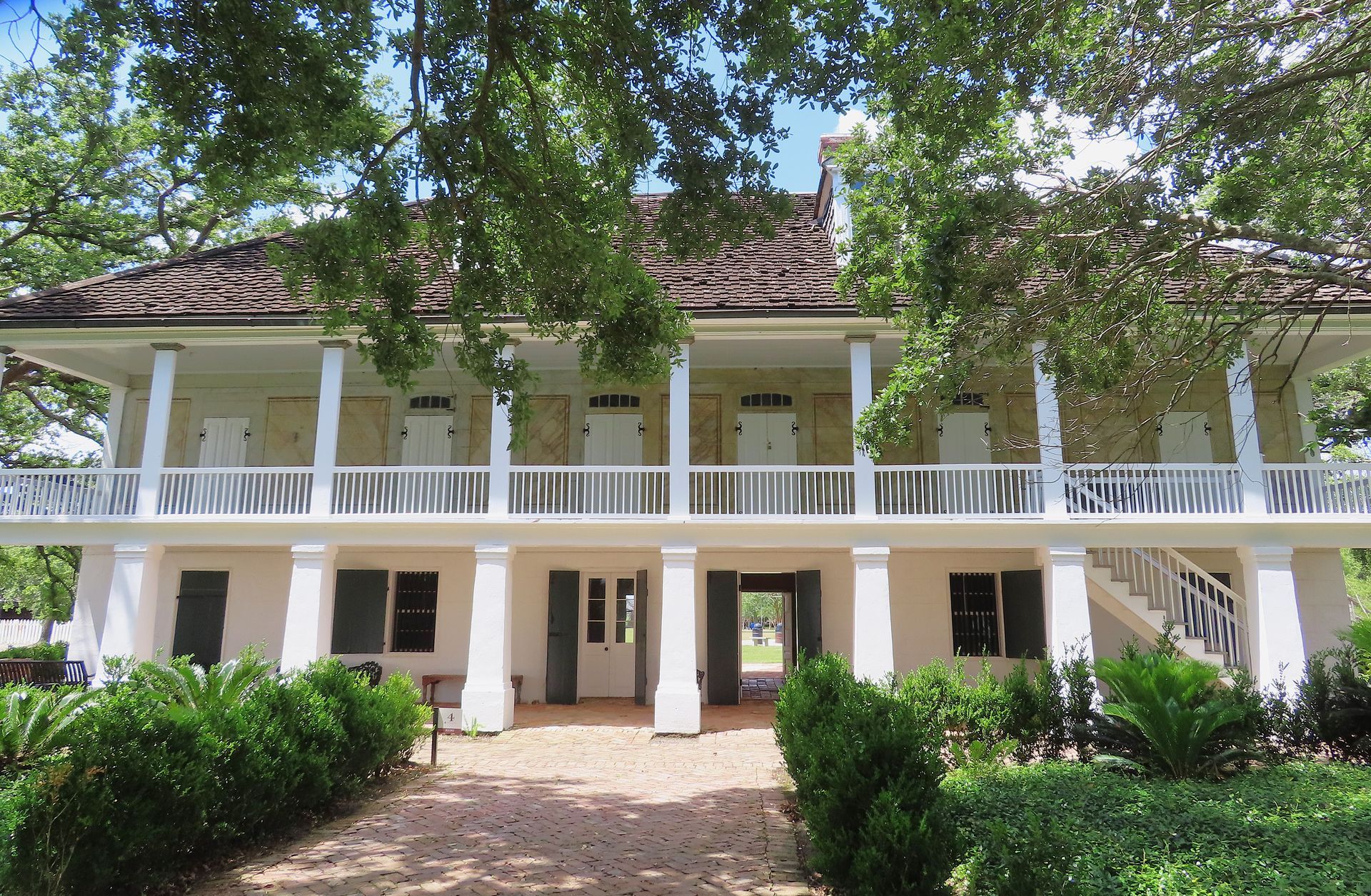 A large white house with a large porch surrounded by trees