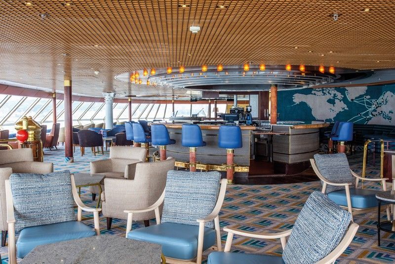 A large room with tables and chairs and a bar on a cruise ship.