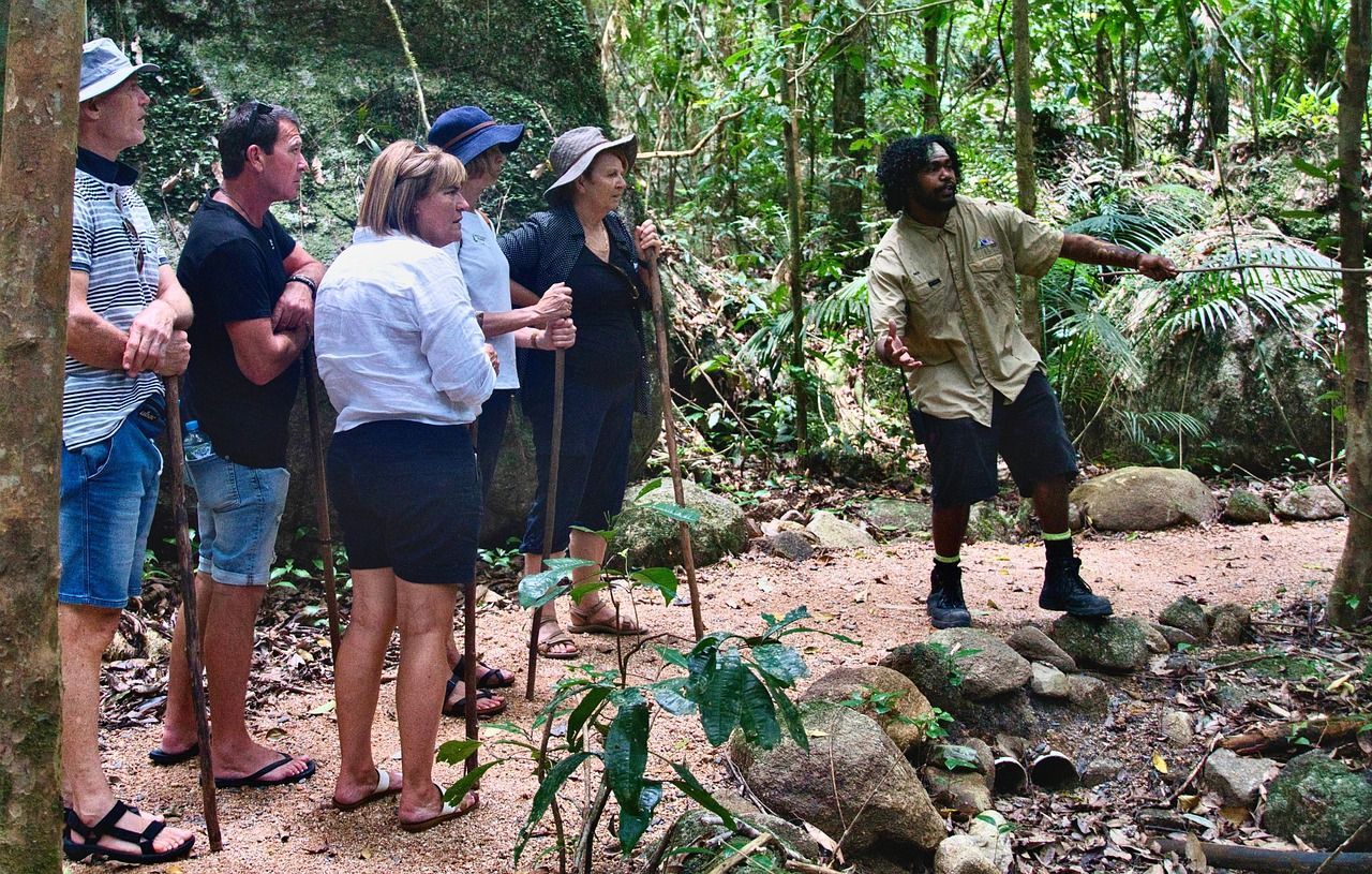 A group of people are standing in the woods talking to a man.