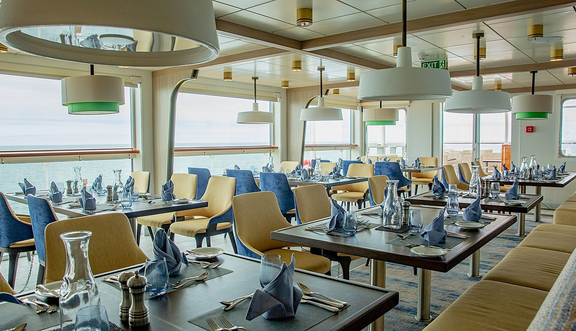 A large dining room filled with tables and chairs with a view of the ocean onboard Sylvia Earle