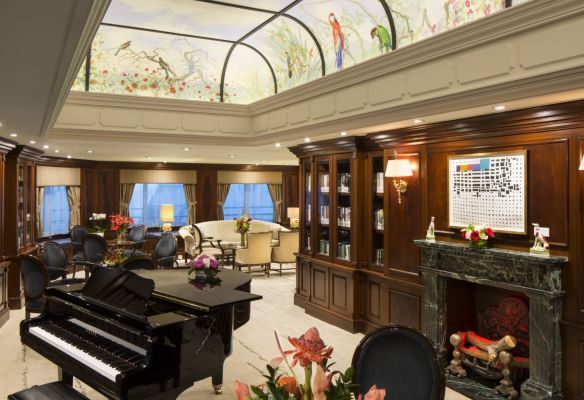 a living room with a piano and a fireplace on Azamara Quest