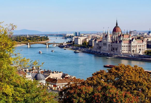 An aerial view of a Budapest with a river in the foreground and a bridge in the background.