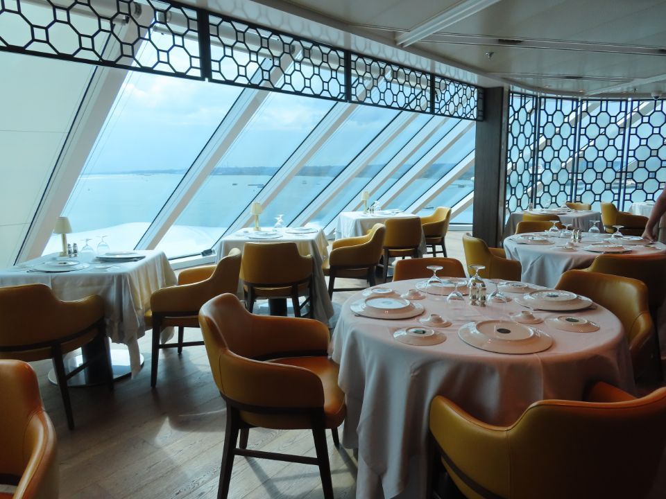 A restaurant with tables and chairs with a view of the ocean