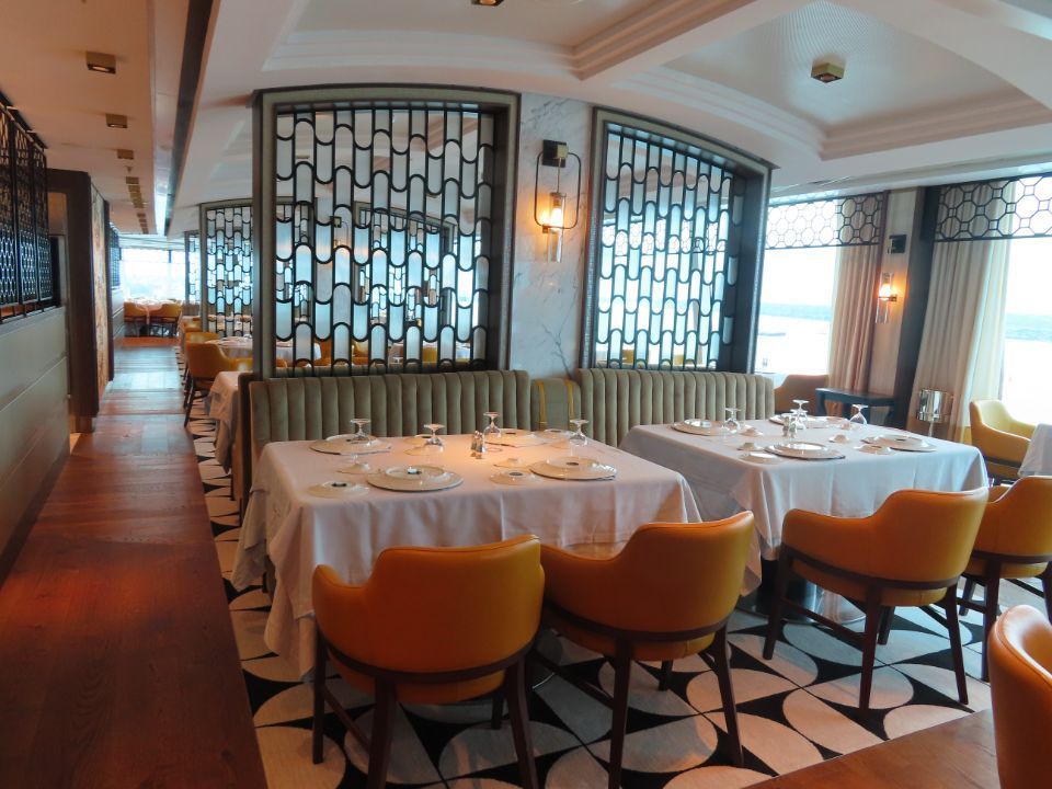 A long hallway with tables and chairs in a restaurant