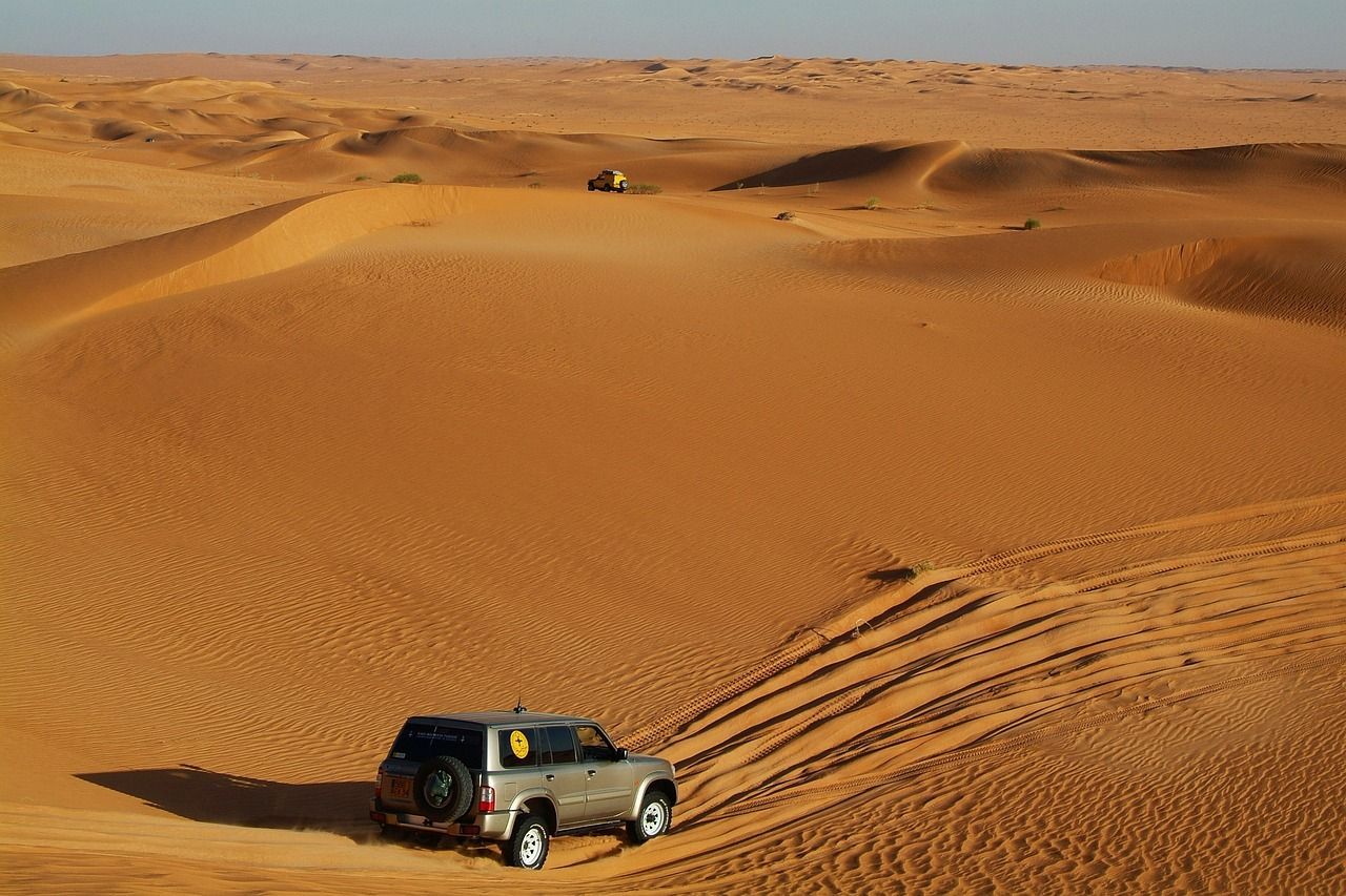 A car is driving on a dirt road in the desert.