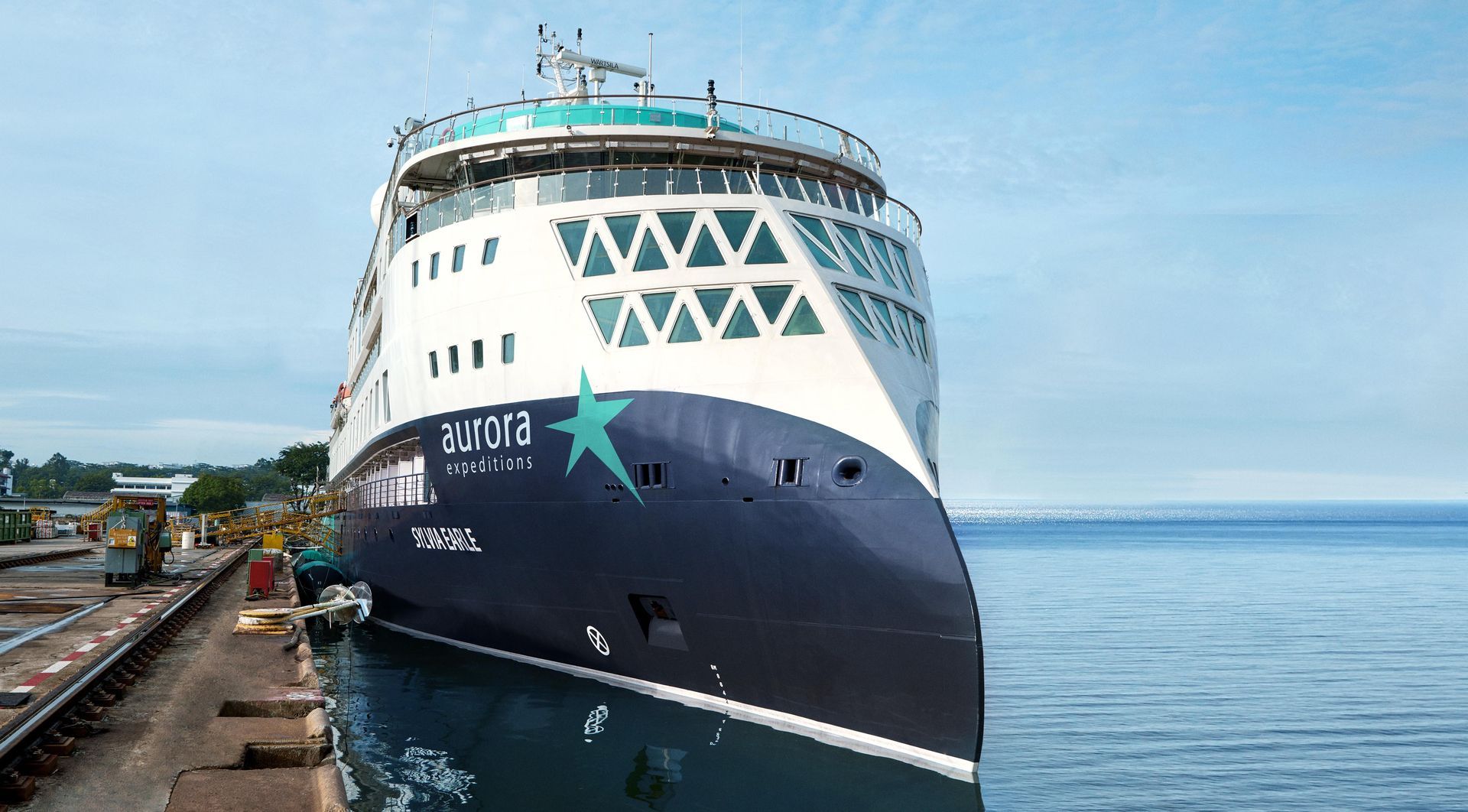 An expedition cruise ship is docked in a harbor.