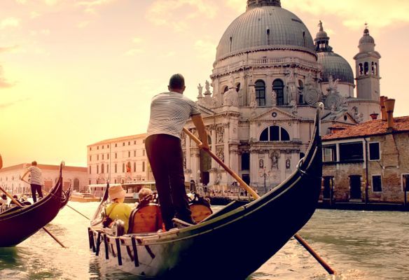 a man is rowing a gondola down a river in venice , Top Romantic Ports - Venice, Italy