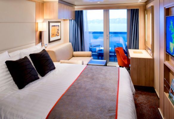 a cruise ship cabin with a bed , couch , desk and television .