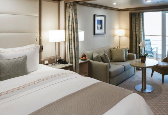A cruise ship suite with a bed , couch , table and chairs