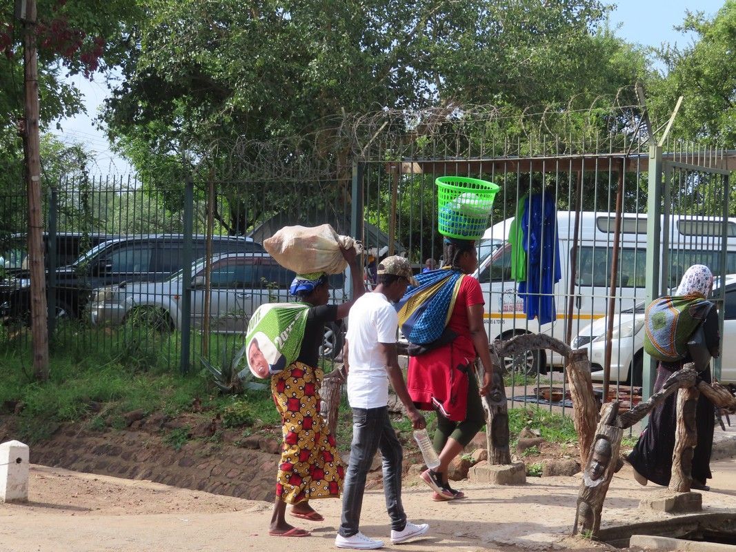A group of people are walking down a street with baskets on their heads.