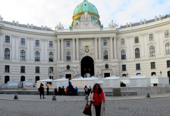 A woman stands in front of a large white building with a green dome