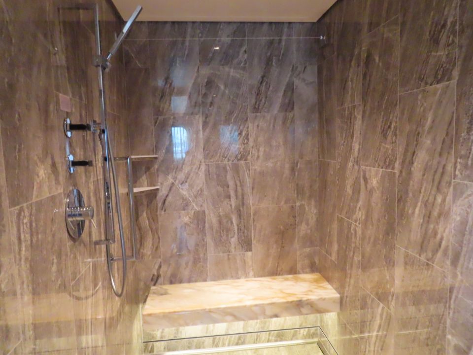 A bathroom with a walk in shower and a bench.