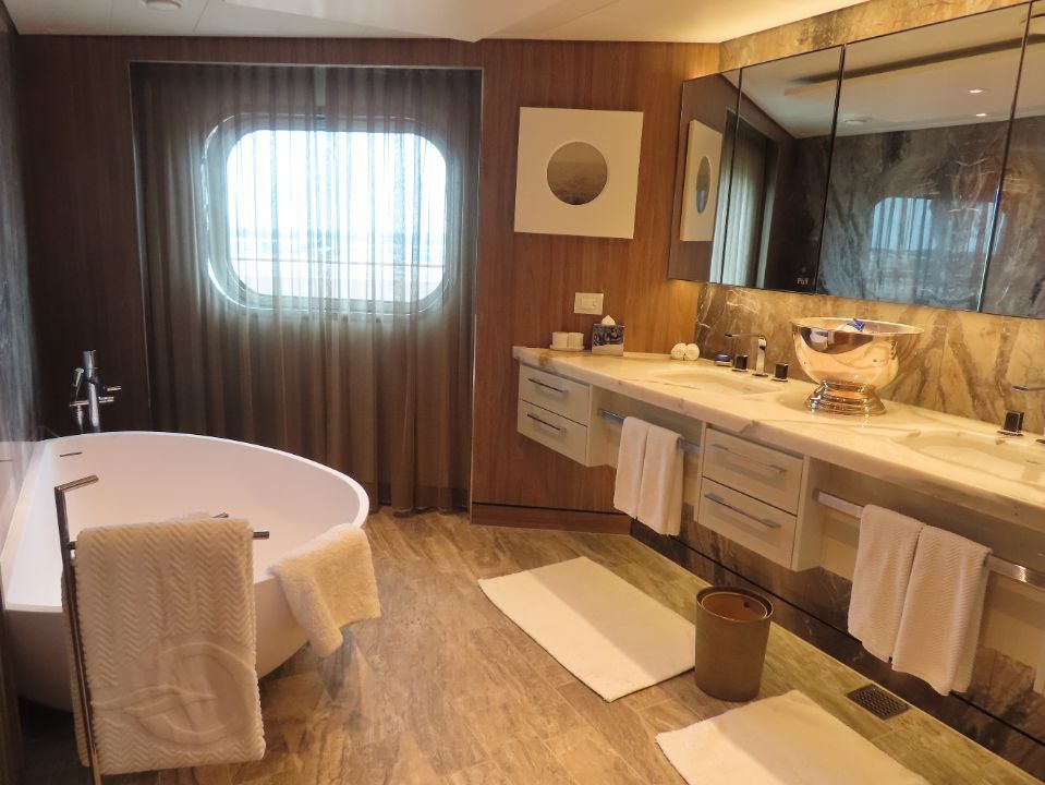 A bathroom with two sinks , a tub and a window.