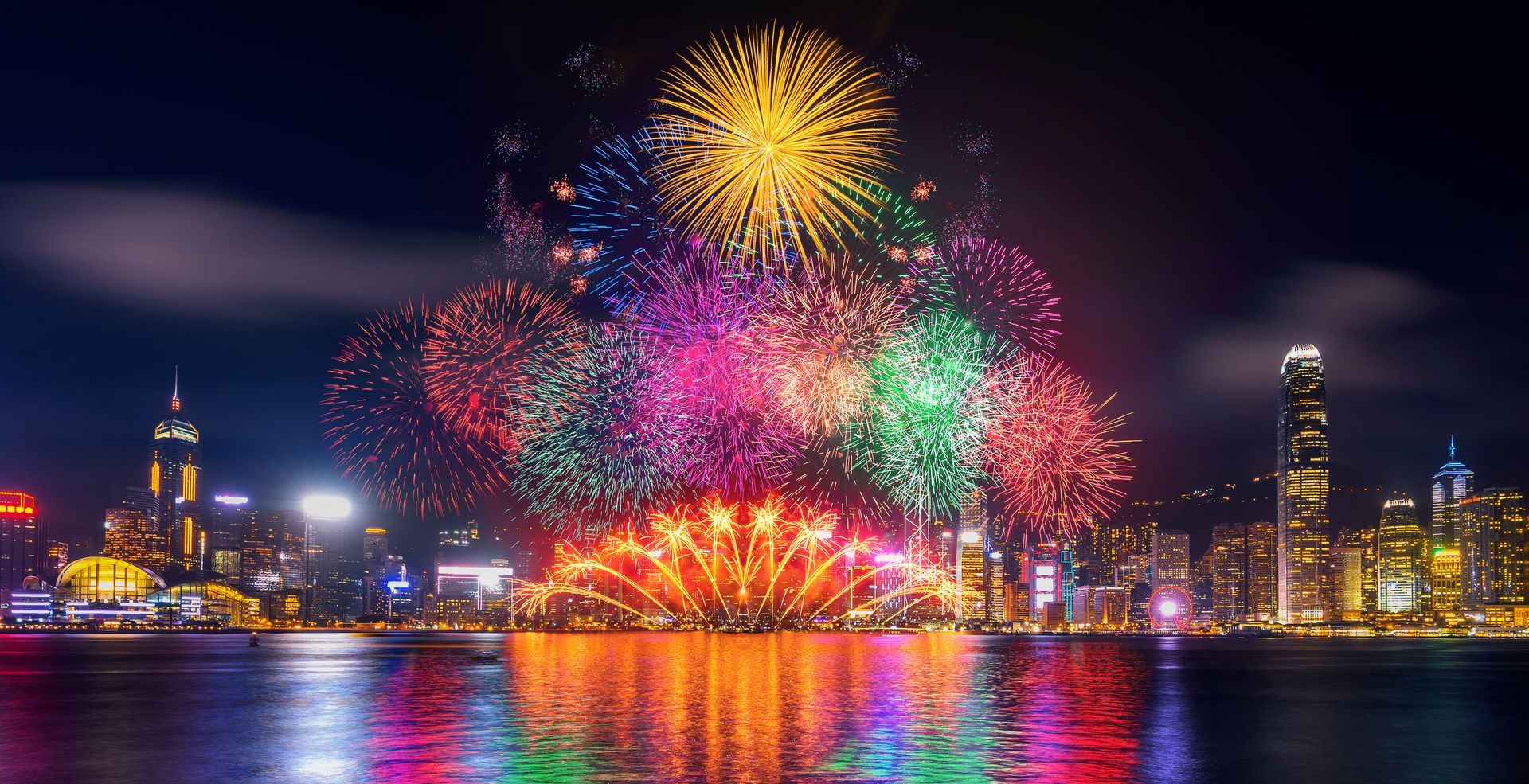 fireworks are displayed over a body of water in front of a city skyline in Hong Kong for Chinese New Year 