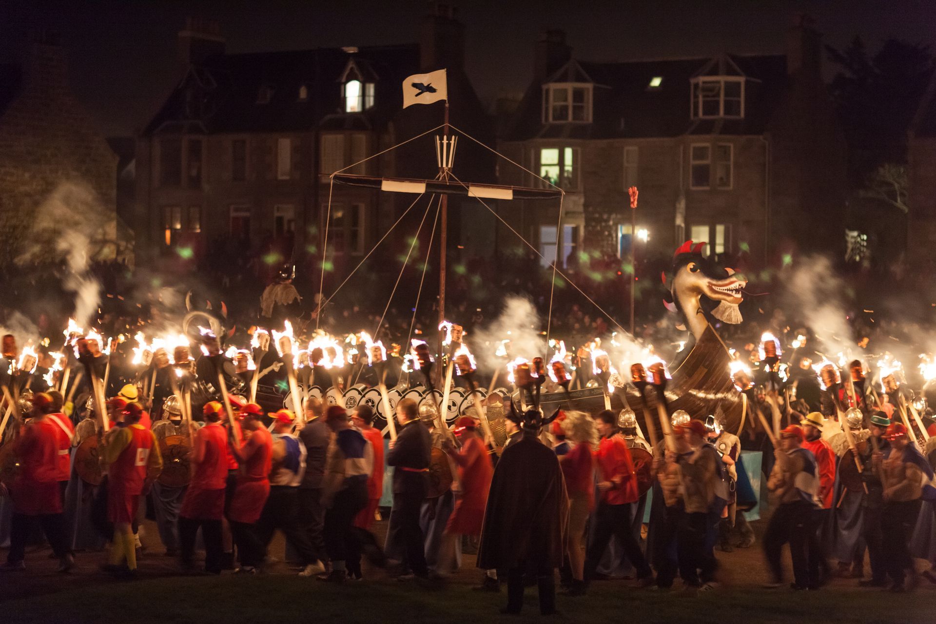 a group of people are holding torches in front of a large viking ship Up Helly Aa festival