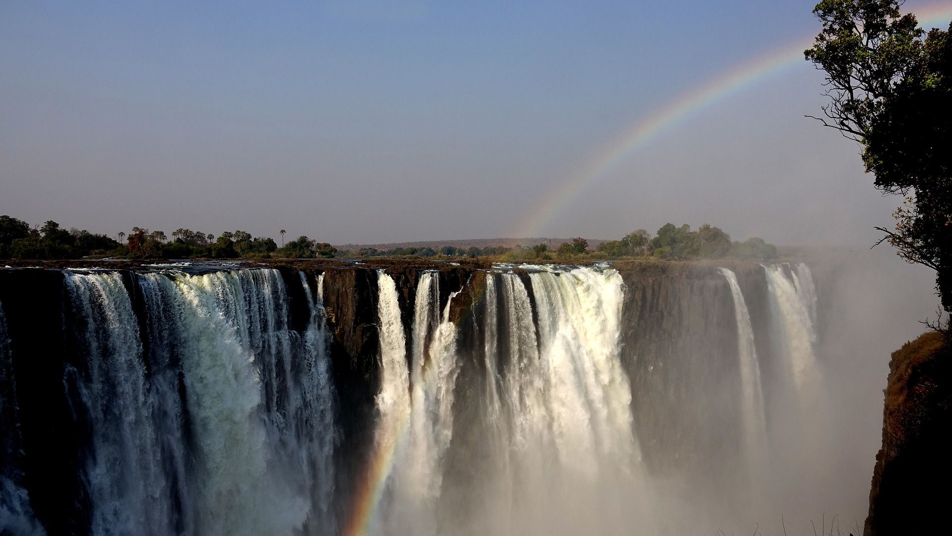 A waterfall with a rainbow in the background in Zimbabwe