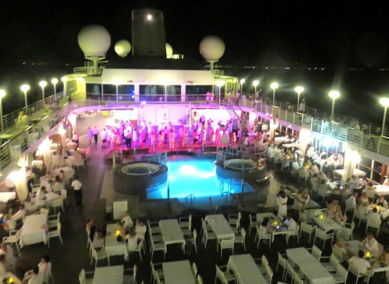 a group of people are dancing in front of a large pool on Azamara Quest