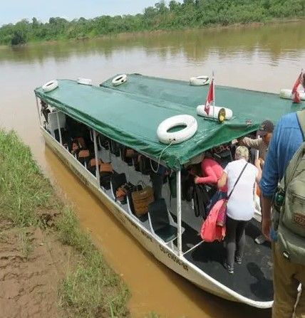 A group of people are boarding a boat on a river in Peru