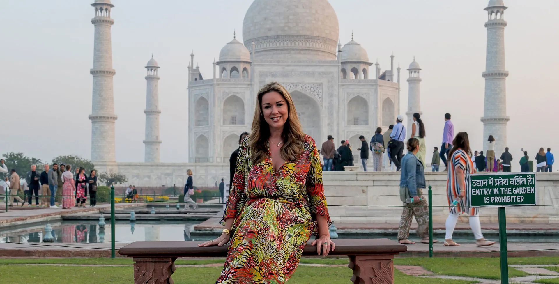 A woman is sitting on a bench in front of the taj mahal.