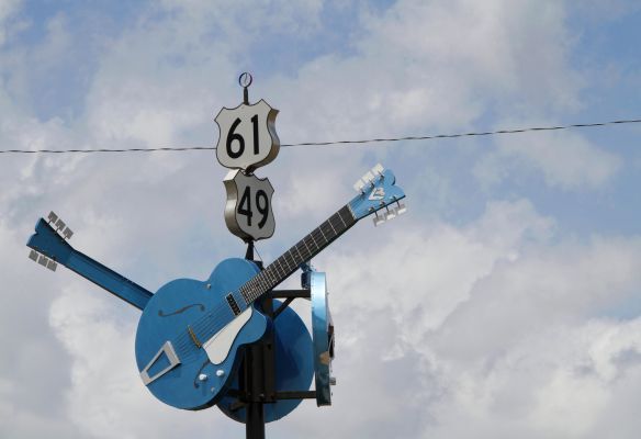 a blue guitar is sitting on top of a road sign at Clarksdale, Mississippi