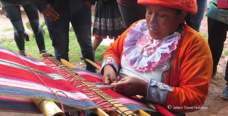 A woman is sitting at a table making a blanket.