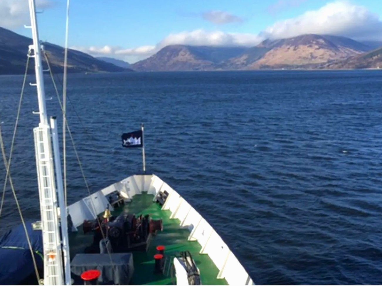 Cruising the Scottish Lochs Boat sailing on a blue lake with mountains in the background on a sunny day.