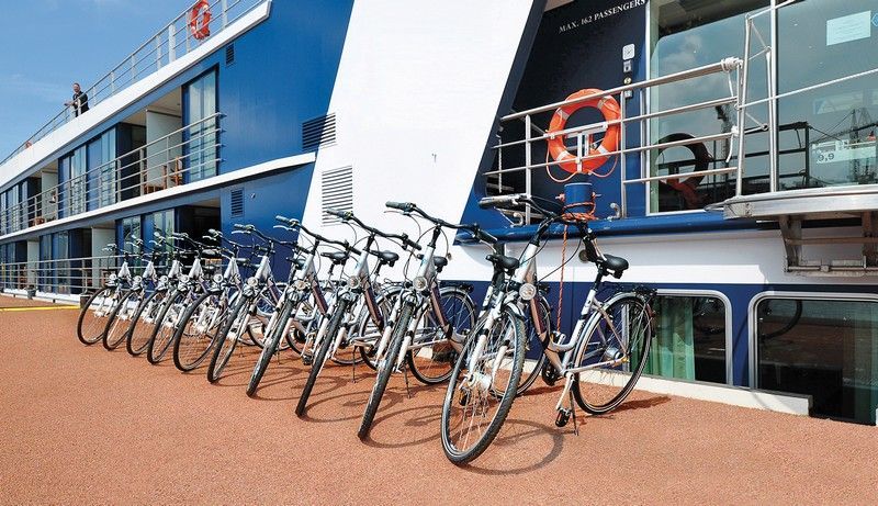 a row of bicycles are parked in front of a river cruise ship .