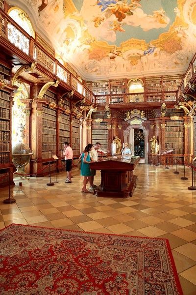 a couple of people are standing in a library looking at books .