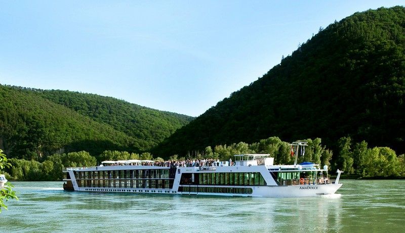 a boat is floating on a river with mountains in the background .