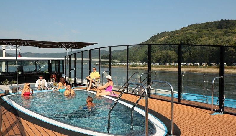 a group of people are swimming in a large swimming pool on a river cruise