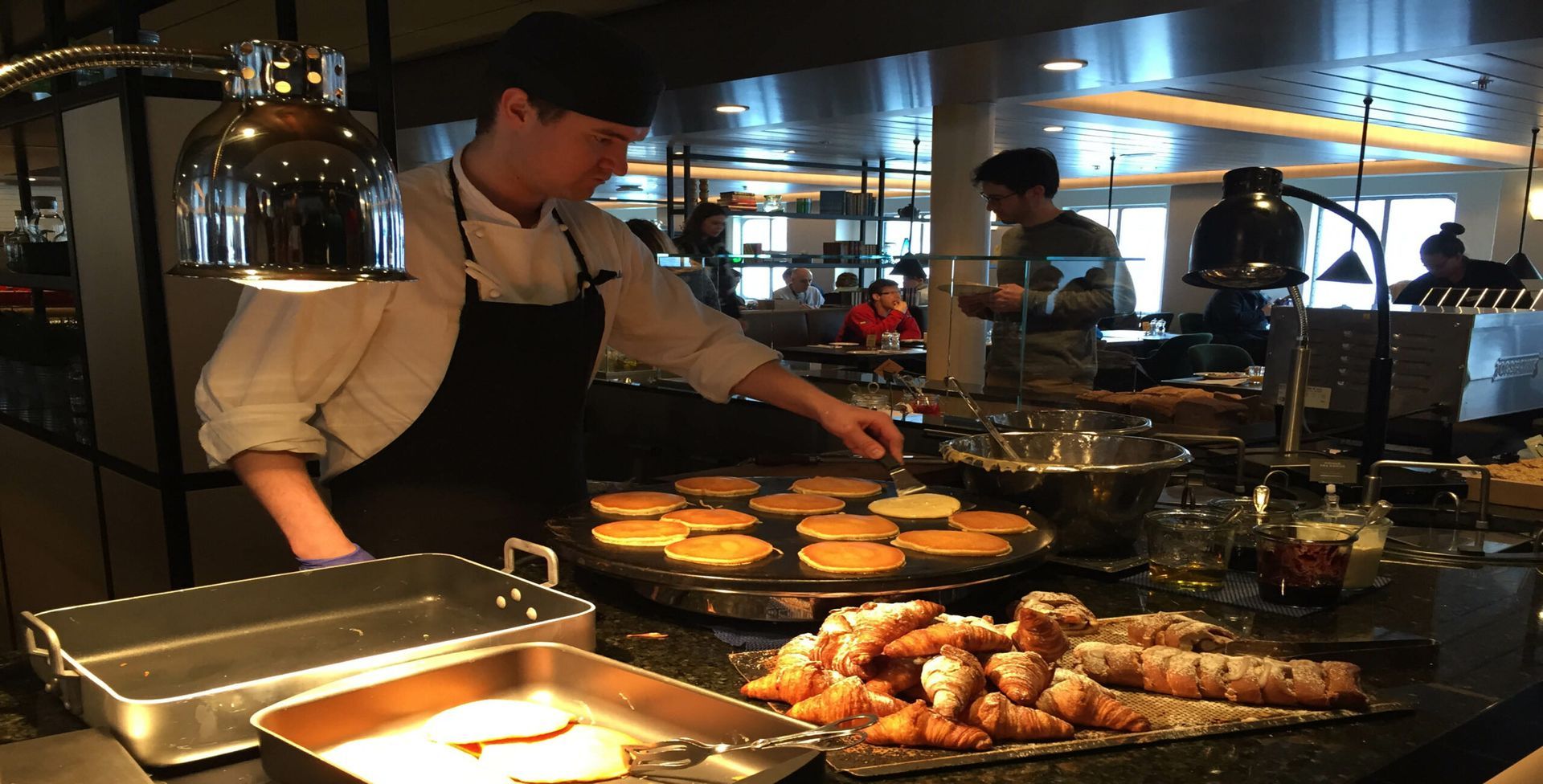 A man is cooking pancakes in a restaurant kitchen