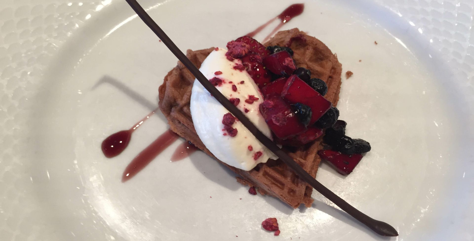 A white plate topped with a dessert with whipped cream and berries