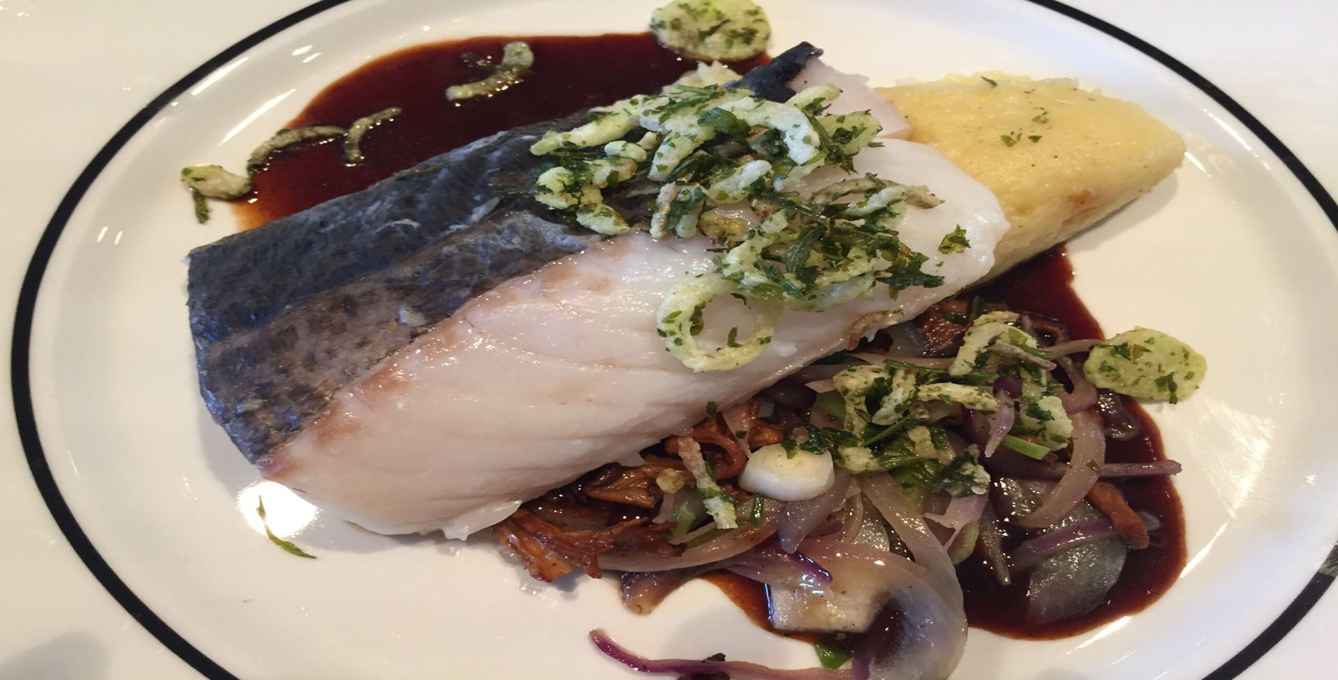 A white plate topped with a piece of fish and sauce.