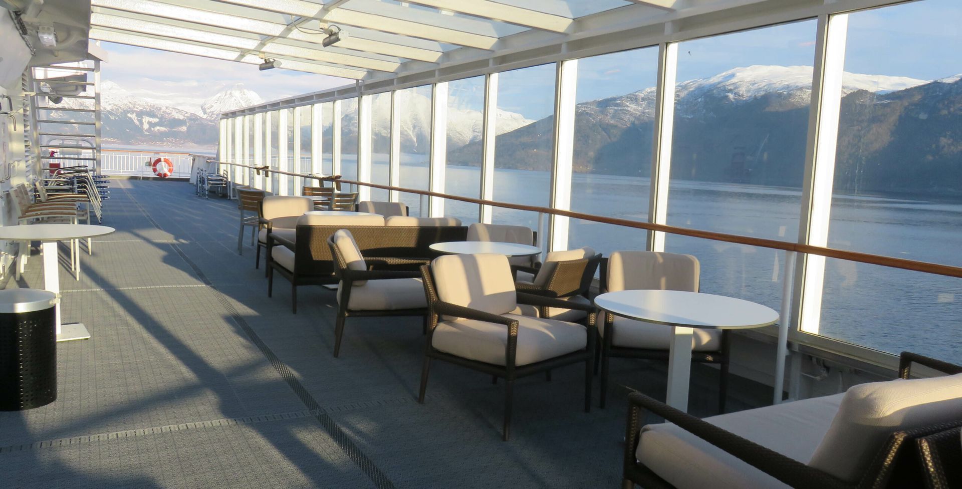A balcony with tables and chairs overlooking a body of water