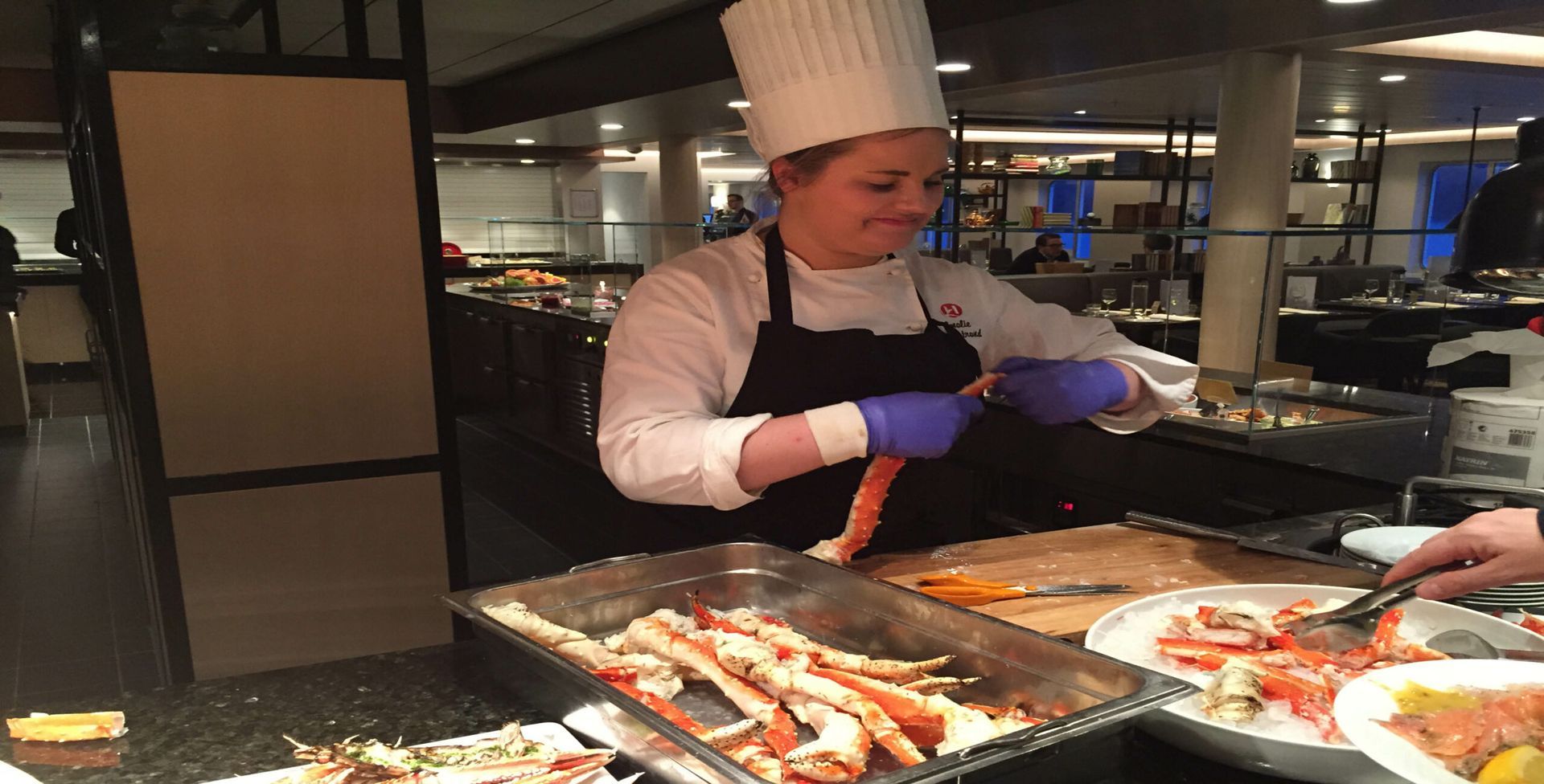 A woman in a chef 's hat is preparing food in a restaurant.