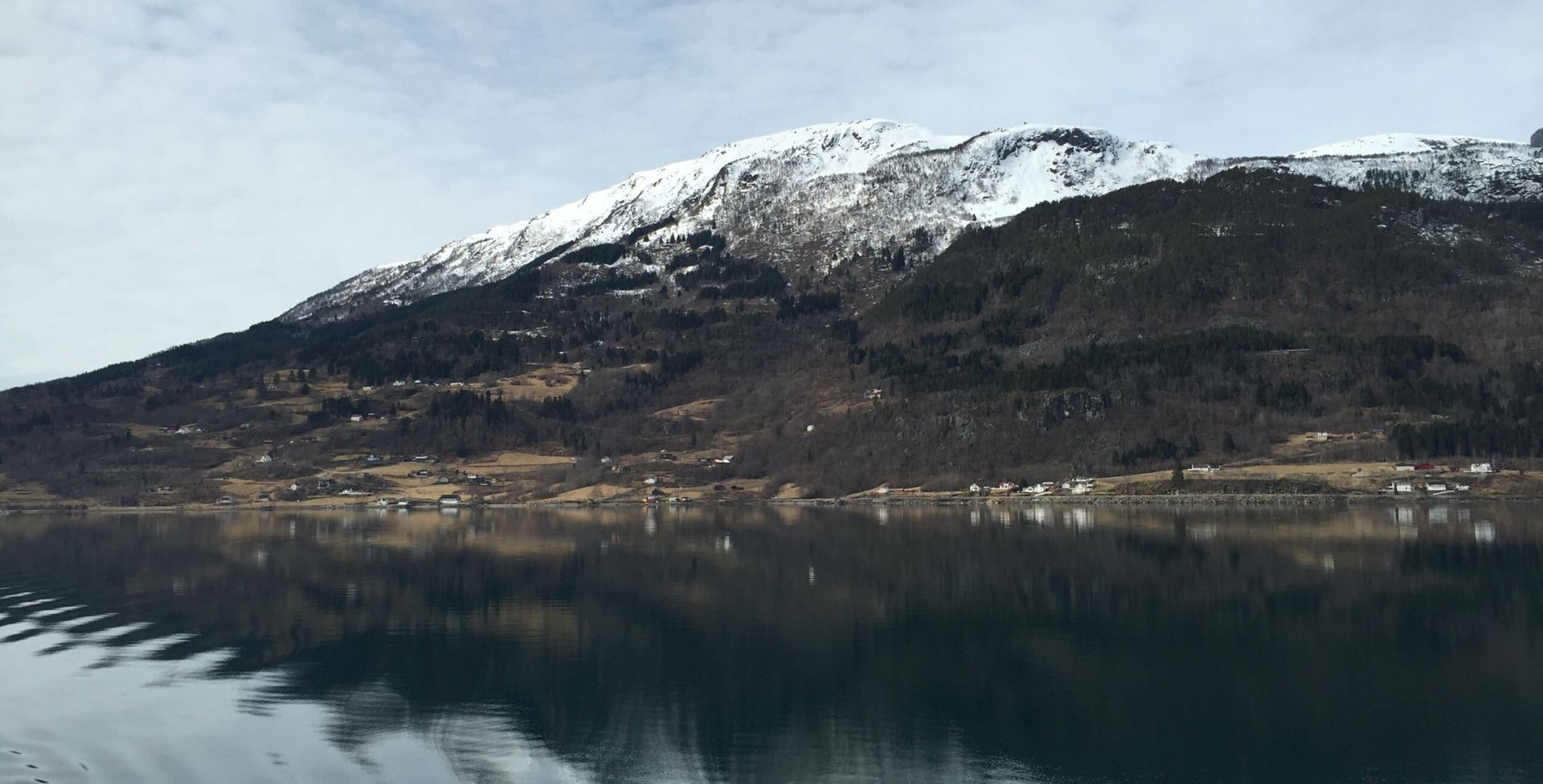 A snowy mountain is reflected in the water of a lake.