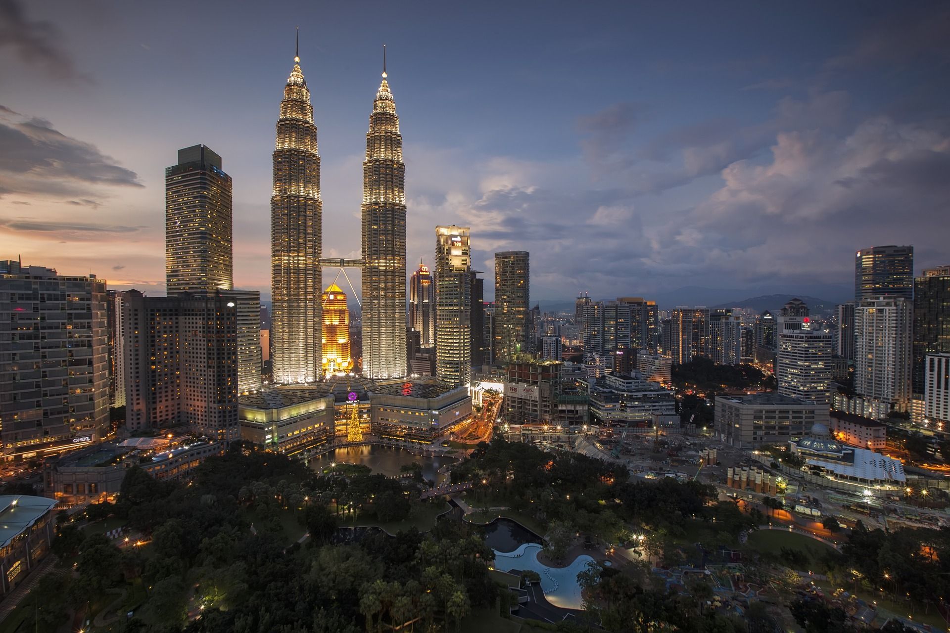 An aerial view of a city skyline at night with a park in the foreground in Kuala Lumpur